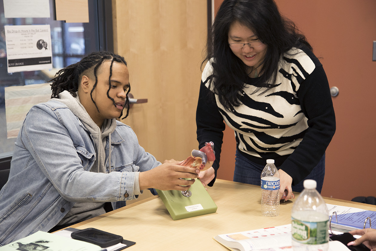 Two smiling students are meeting with a tutor.