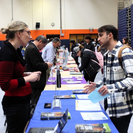 Student speaking with transfer advisor during transfer fair in a gymnasium