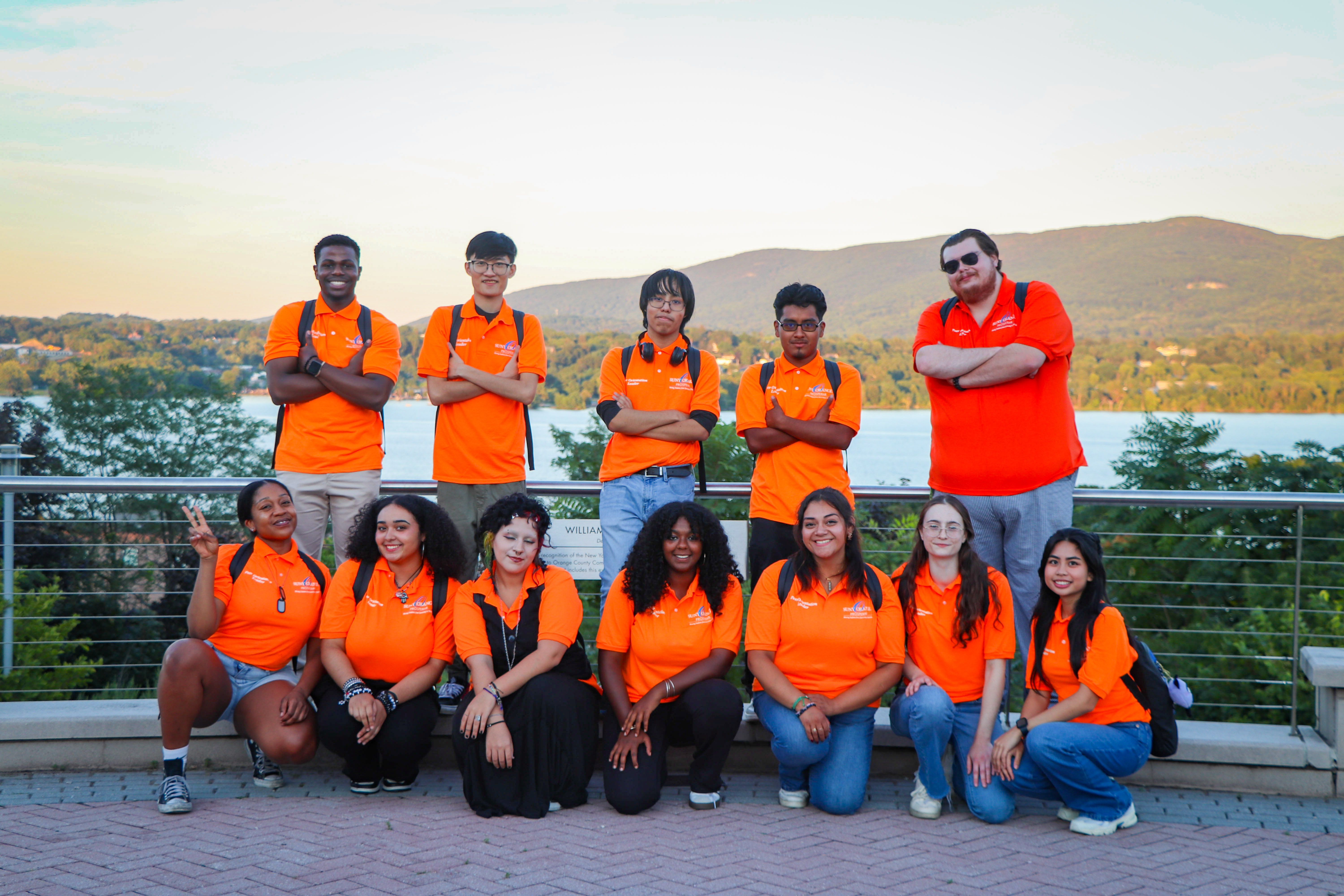 a group of students in bright orange SUNY Orange polos standing together at student orientation