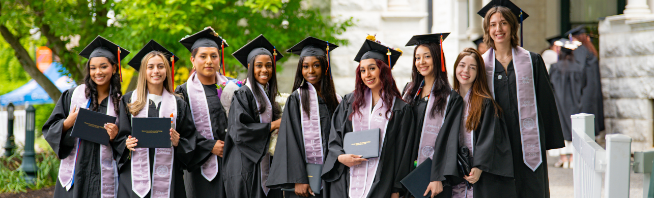 Dental Hygiene graduates in graduation regalia holding diplomas