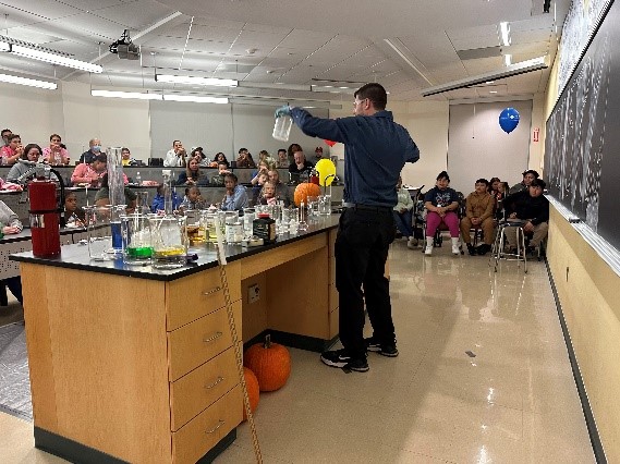 Dr. McCall showing kids two large beakers