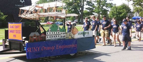 Faculty and students marching behing float carring Vin Fiz replica during Middletown parade.